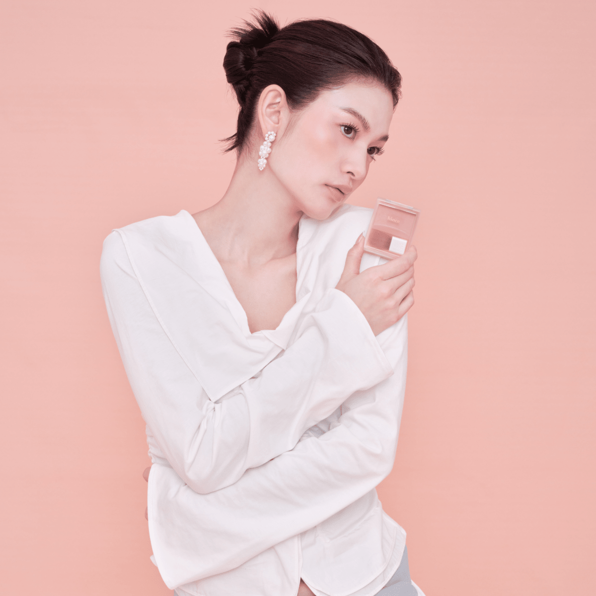 Hince Hug Layer Cheek Blush in a soft pink shade, showcasing its smooth, blendable powder formula on a mirrored compact.