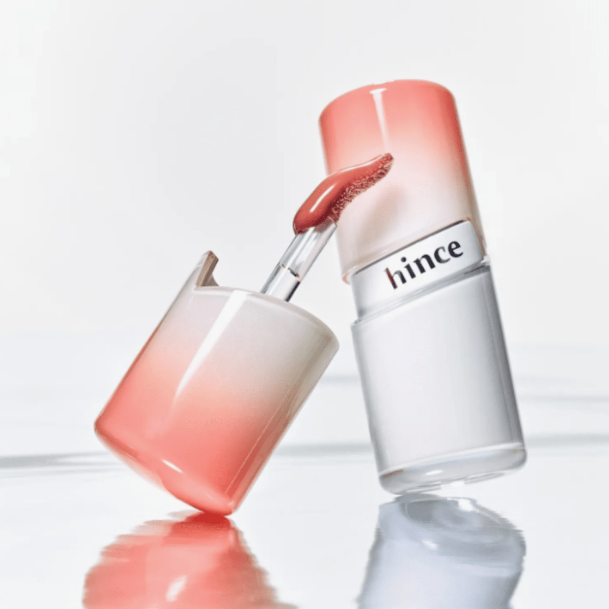 Hince Mirror Dew Gloss lip gloss tube with reflective packaging, showcasing shiny, hydrating lip color in a sleek design.
