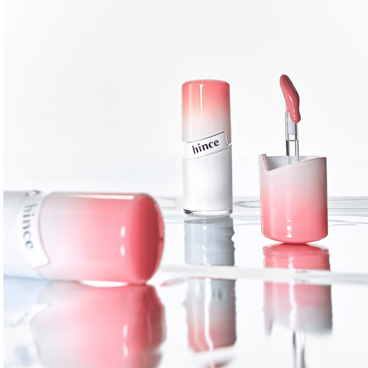 Hince Mirror Dew Gloss lip gloss with reflective shine in a sleek tube, showcasing its glossy finish and vibrant color.