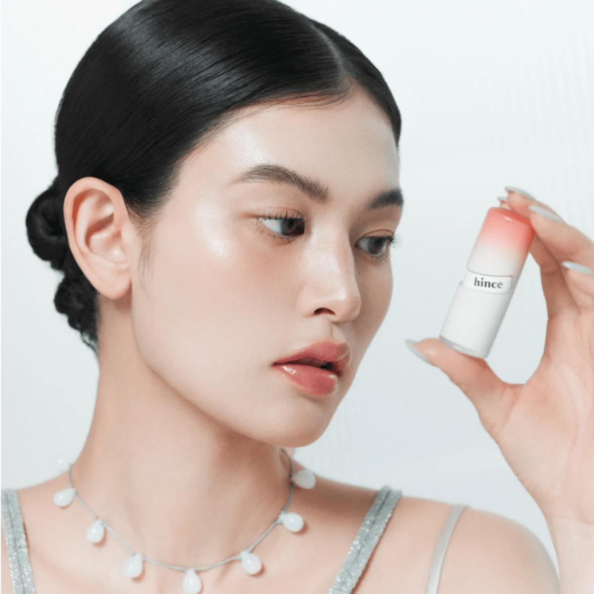Hince Mirror Dew Gloss lip gloss in a clear tube with reflective mirror-like finish, showcasing glossy, moisturizing lip shine.